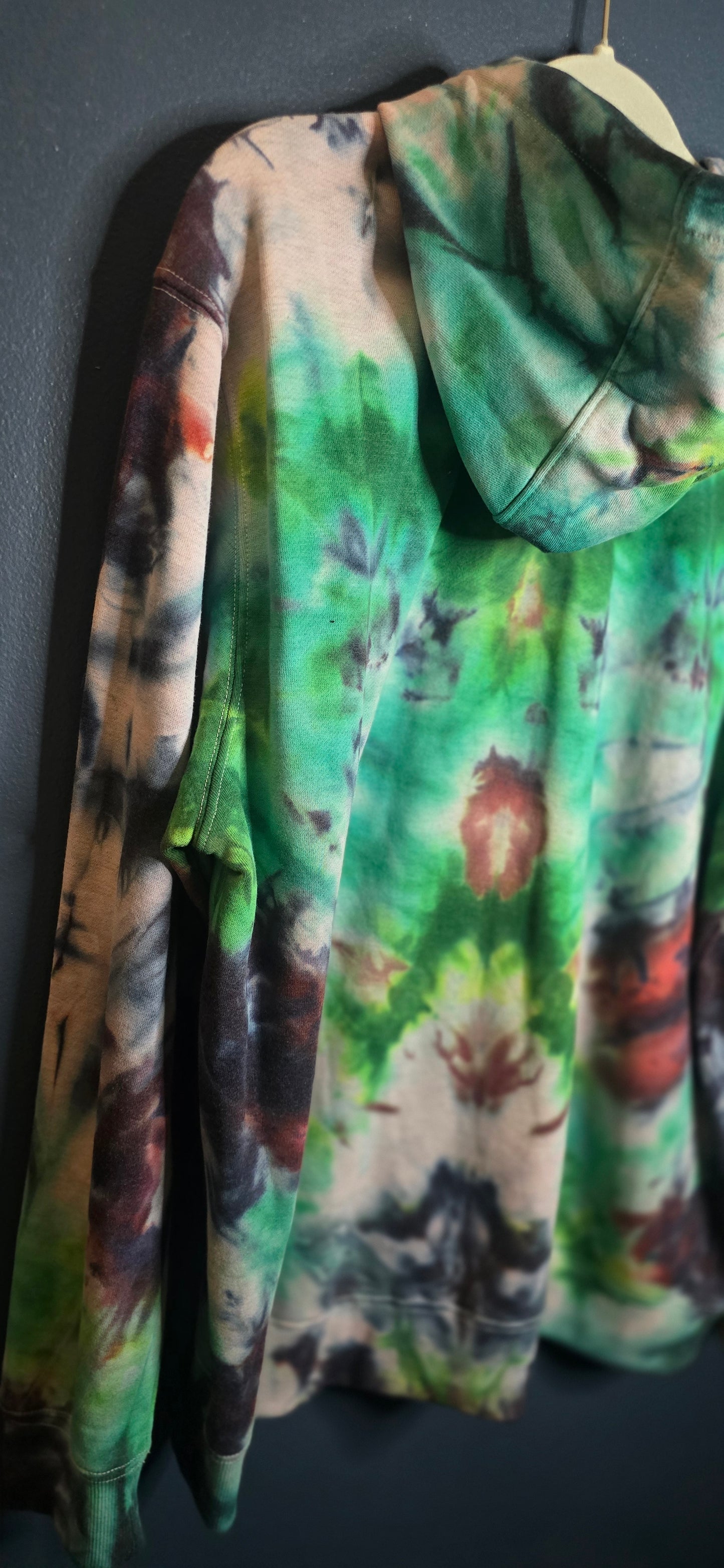 Folded tie-dye fabric with green, purple, and brown colors on a dark surface